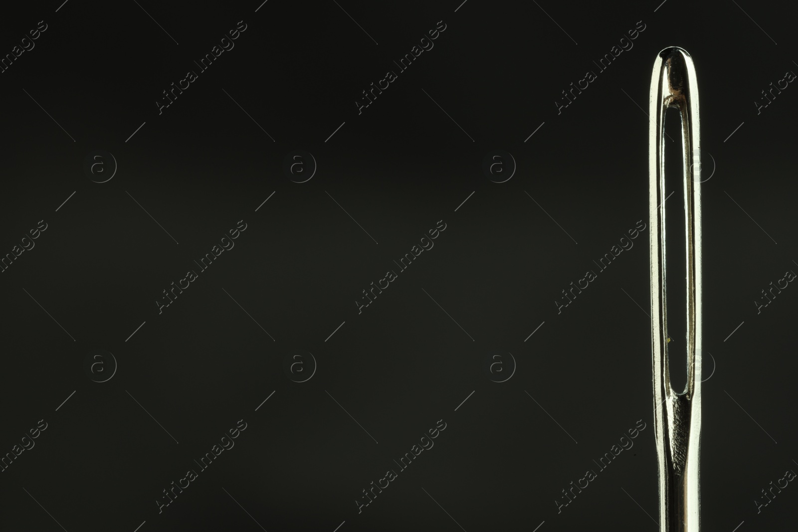 Photo of Sewing needle on black background, closeup view. Space for text