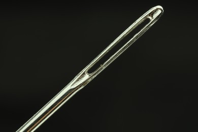 Photo of Sewing needle on black background, closeup view