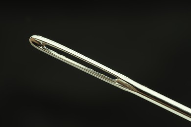 Photo of Sewing needle on black background, closeup view