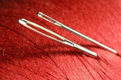 Photo of Spool of red sewing thread with needles, macro view