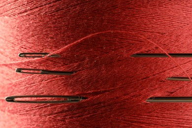 Spool of red sewing thread with needles, macro view