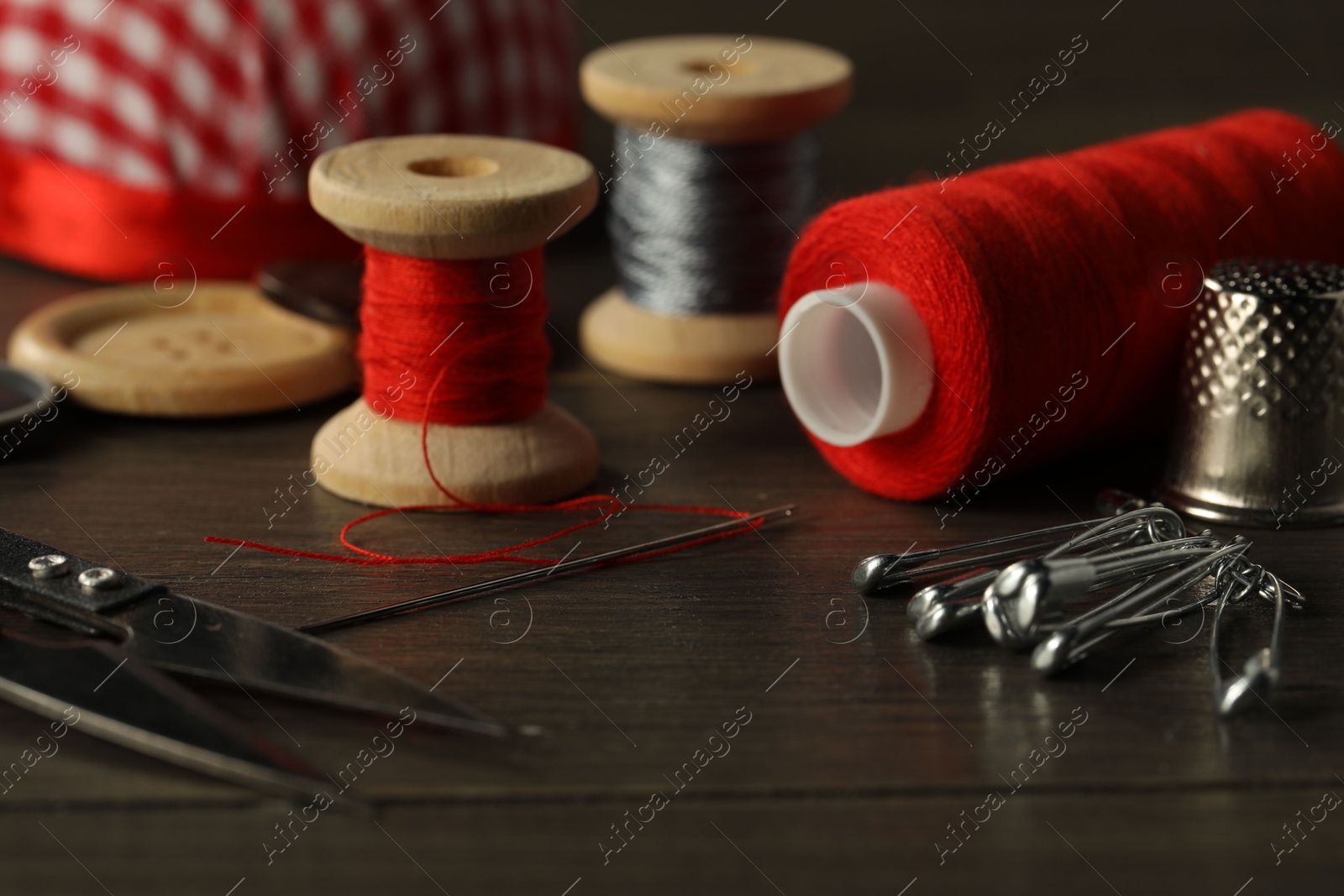 Photo of Different sewing tools on wooden table, closeup