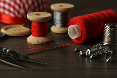 Different sewing tools on wooden table, closeup