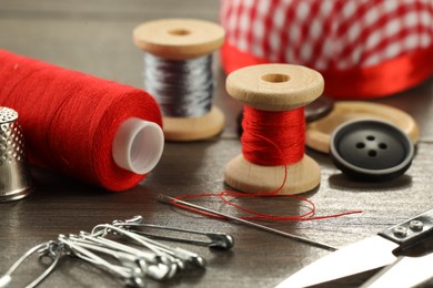 Photo of Different sewing tools on wooden table, closeup