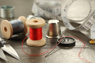 Different sewing tools on wooden table, closeup