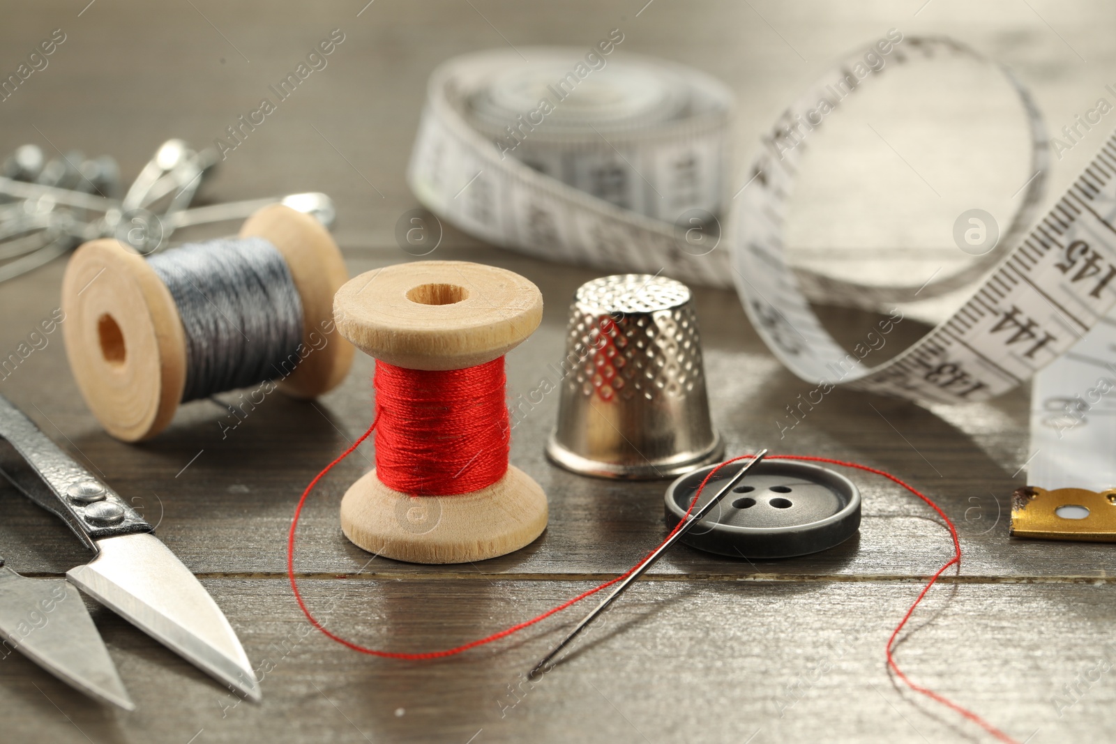 Photo of Different sewing tools on wooden table, closeup