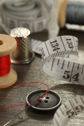 Photo of Different sewing tools on wooden table, closeup