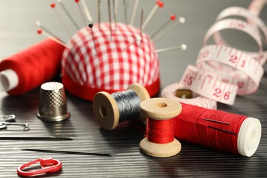 Photo of Different sewing tools on wooden table, closeup