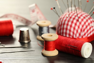 Photo of Different sewing tools on wooden table, closeup