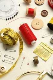 Photo of Different sewing tools on white textured table, above view