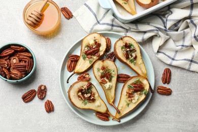 Tasty baked pears with nuts, blue cheese, thyme and honey on light grey table, flat lay