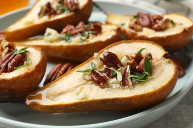 Tasty baked pears with nuts, blue cheese, thyme and honey on table, closeup