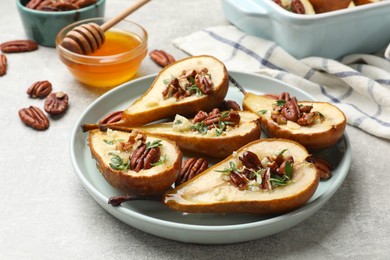 Tasty baked pears with nuts, blue cheese, thyme and honey on light grey table