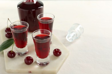 Delicious cherry liqueur and berries on white table