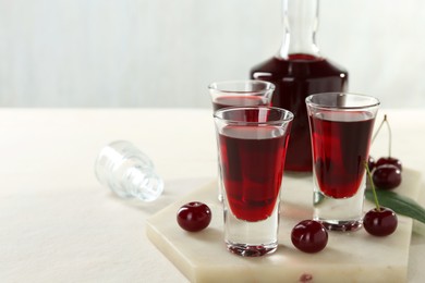 Delicious cherry liqueur and berries on white table