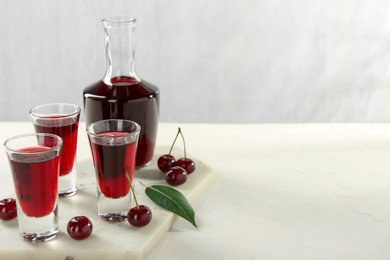 Delicious cherry liqueur and berries on white table. Space for text