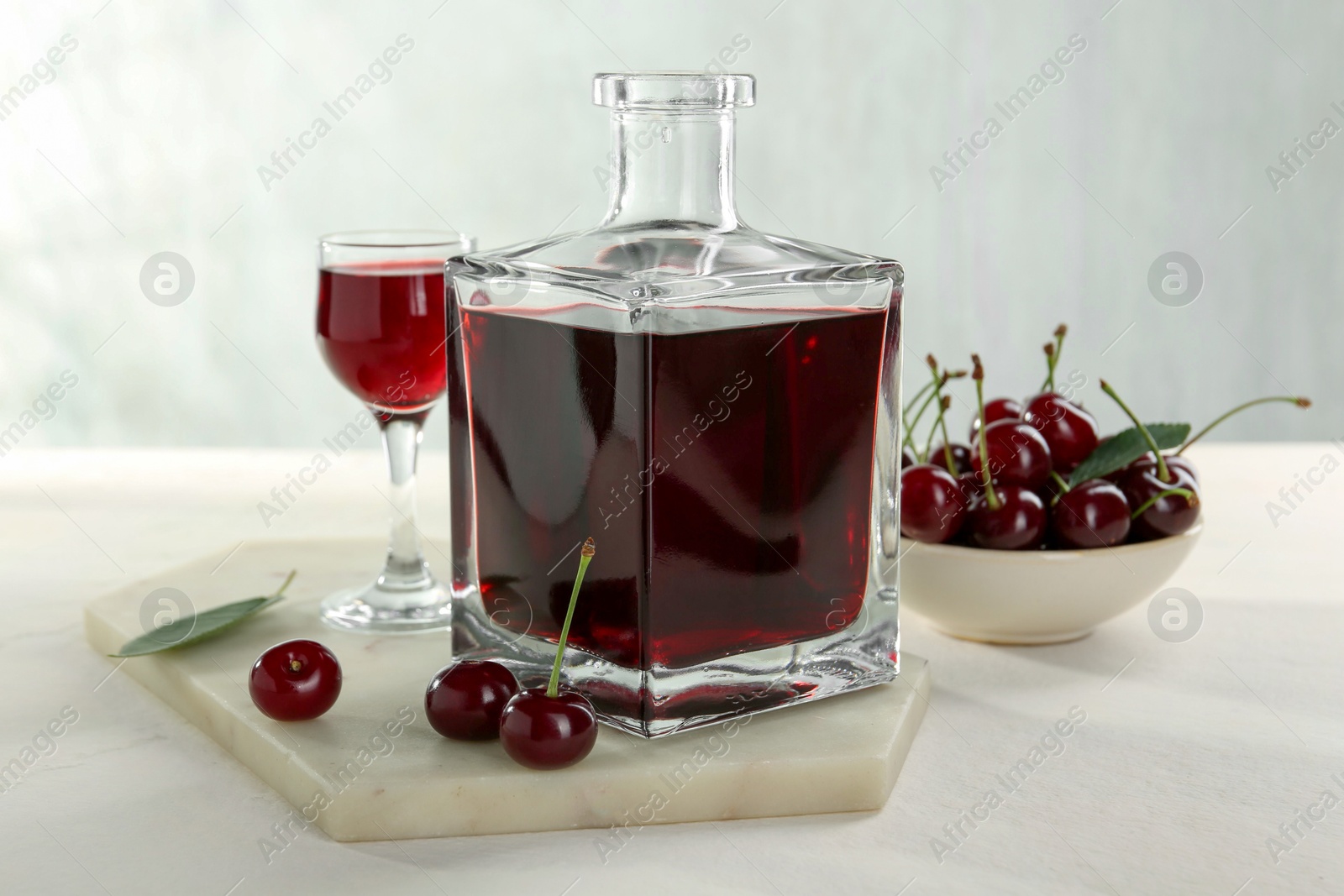 Photo of Delicious cherry liqueur and berries on white table