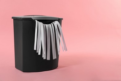 Photo of Shredder with paper strips on pink background, space for text