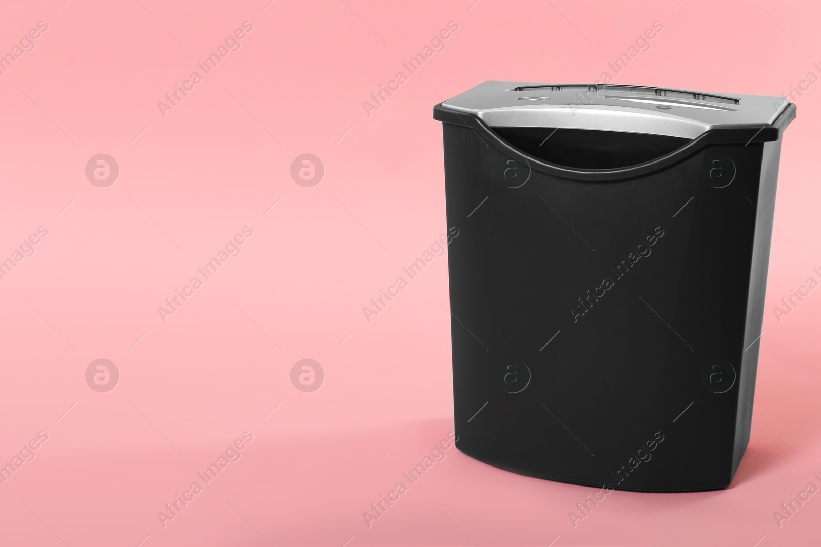 Photo of Paper shredder with basket on pink background, space for text