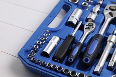 Auto mechanic's tools in plastic box on white wooden table