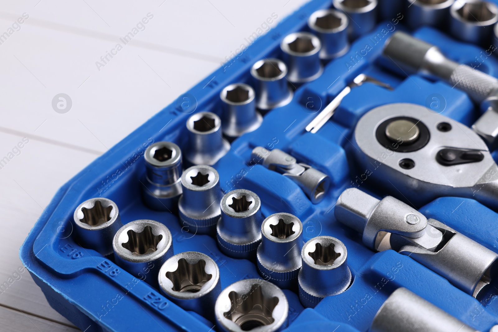 Photo of Auto mechanic's tools in plastic box on white wooden table, closeup