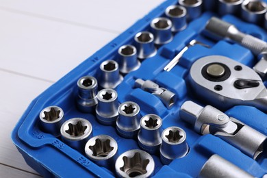 Auto mechanic's tools in plastic box on white wooden table, closeup