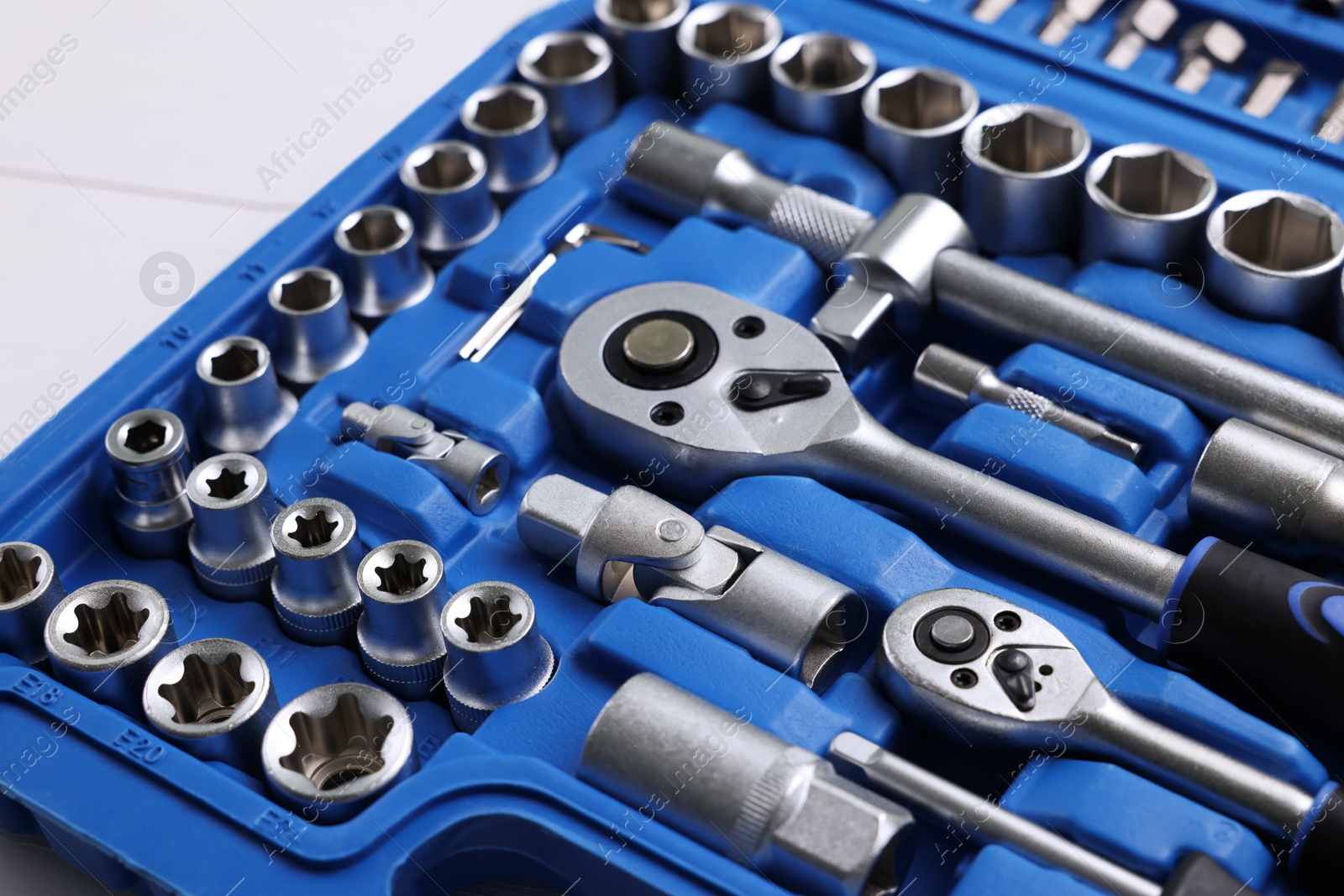 Photo of Auto mechanic's tools in plastic box on white wooden table, closeup