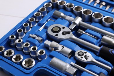 Auto mechanic's tools in plastic box on white wooden table, closeup