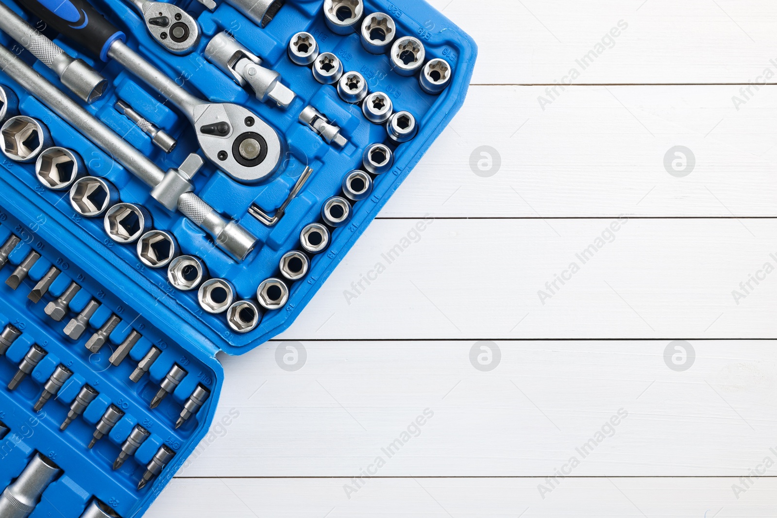 Photo of Auto mechanic's tools in plastic box on white wooden table, top view. Space for text