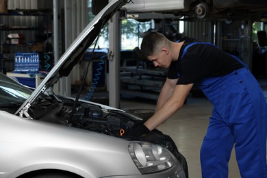 Photo of Young auto mechanic fixing car at automobile repair shop