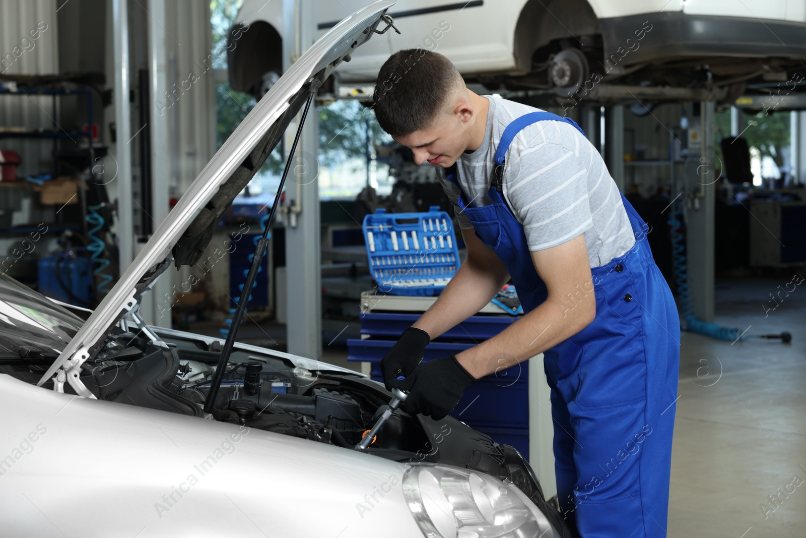 Photo of Young auto mechanic fixing car at automobile repair shop