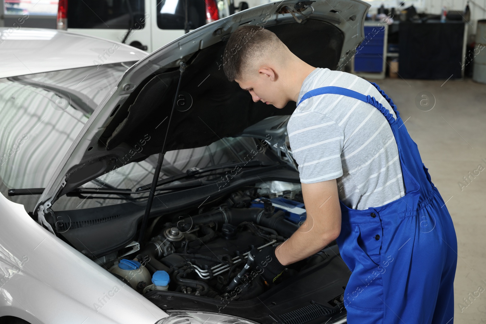 Photo of Young auto mechanic fixing car at automobile repair shop