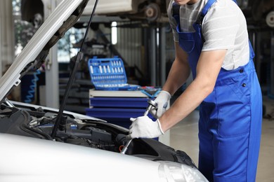 Photo of Auto mechanic fixing car at automobile repair shop, closeup