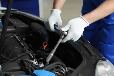 Photo of Auto mechanic fixing car at automobile repair shop, closeup