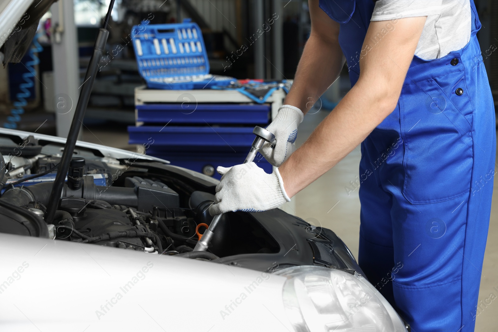 Photo of Auto mechanic fixing car at automobile repair shop, closeup