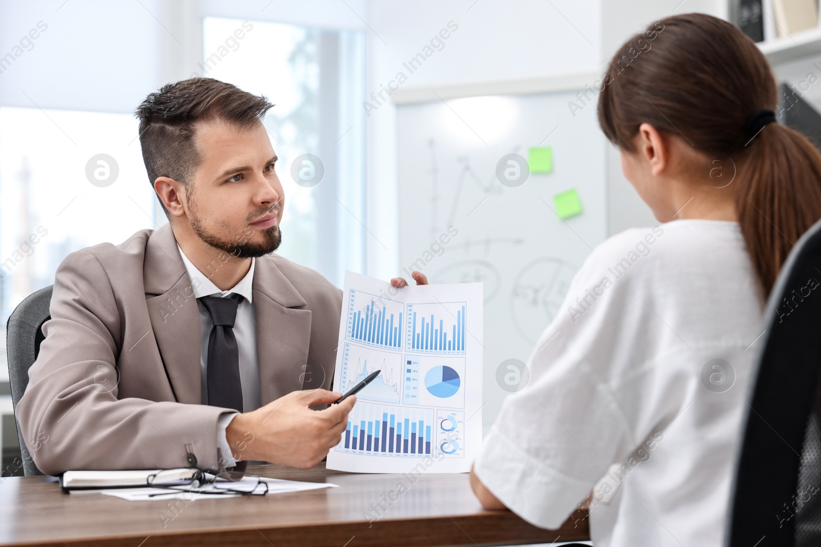 Photo of Consultant working with client at table in office. Business meeting