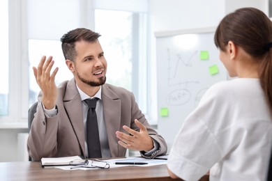 Photo of Consultant working with client at table in office. Business meeting