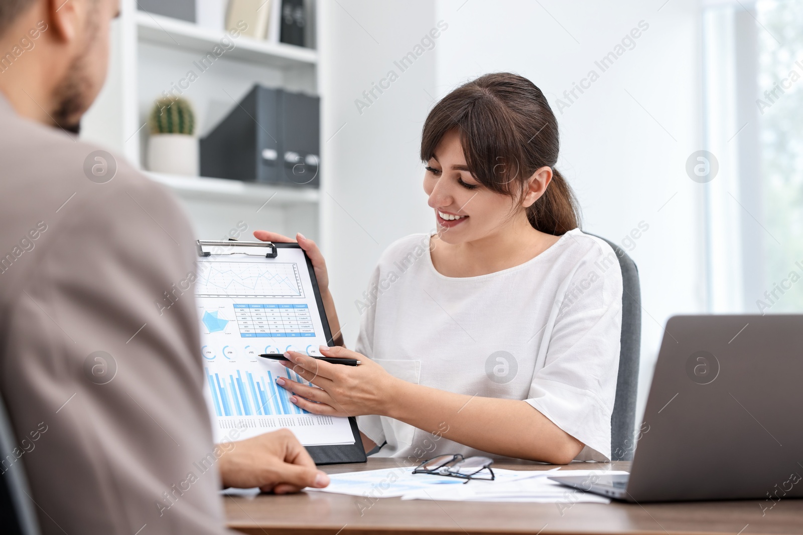 Photo of Smiling consultant working with client at table in office. Business meeting