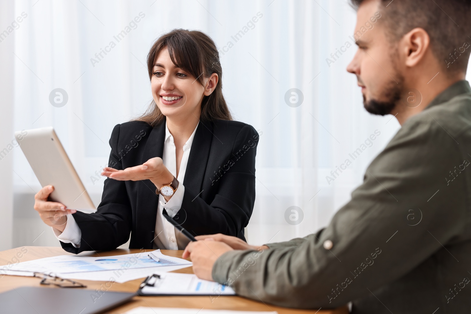 Photo of Smiling consultant working with client at table in office. Business meeting