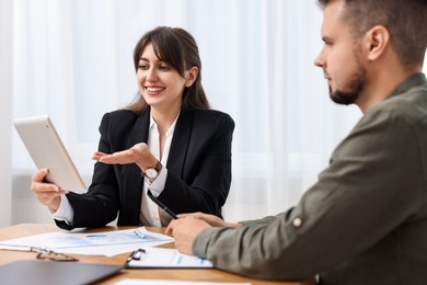 Photo of Smiling consultant working with client at table in office. Business meeting