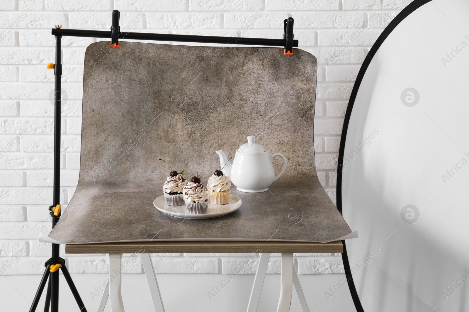 Photo of Cupcakes and tea on table in studio. Professional food photography