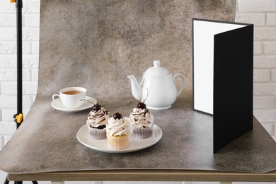 Photo of Cupcakes, tea and light reflector on table in studio. Professional food photography