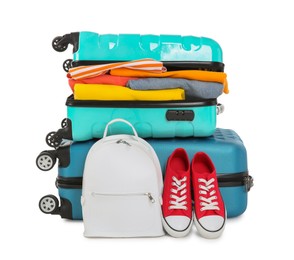 Bright suitcases with clothes, backpack and sneakers isolated on white