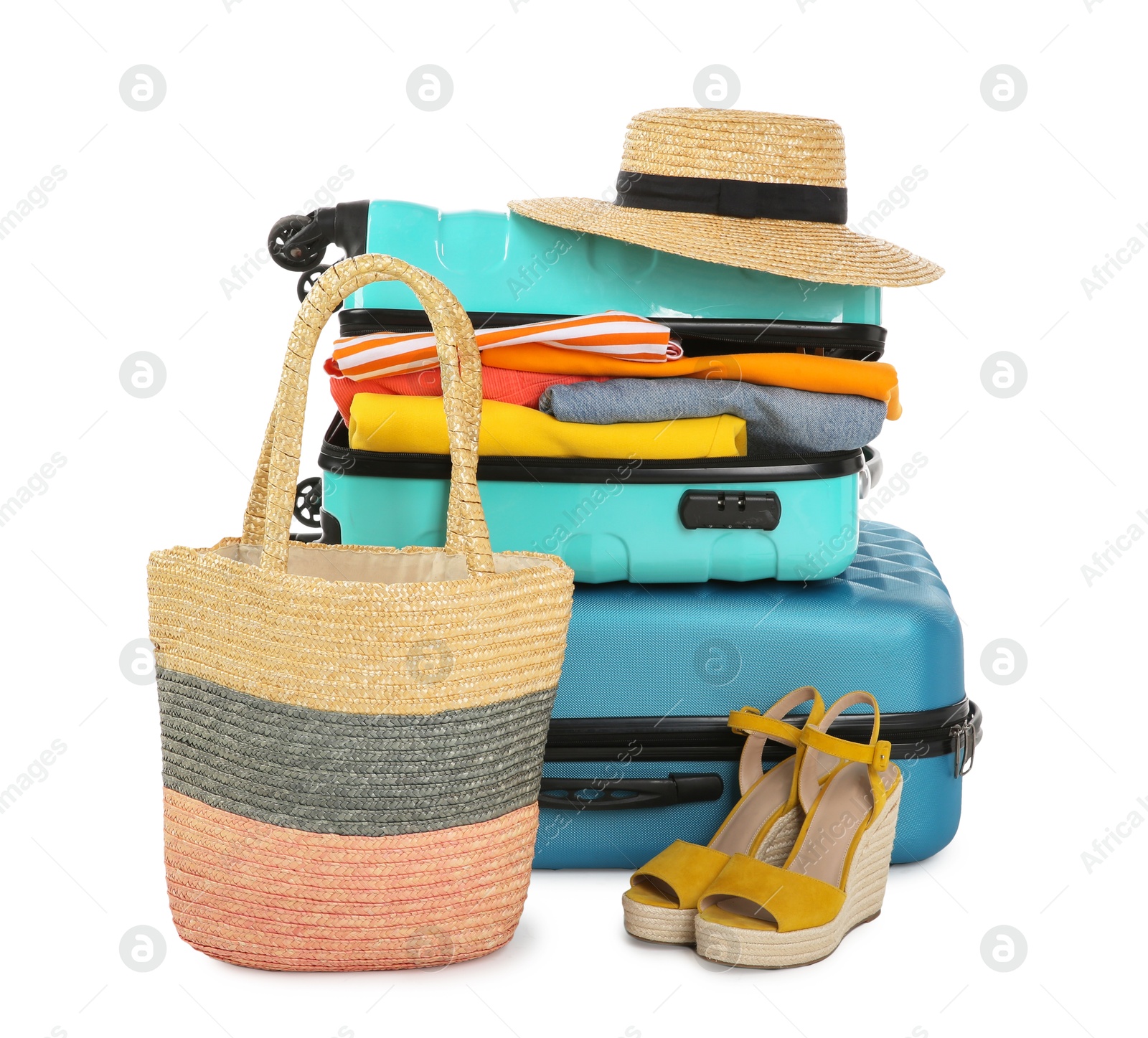 Photo of Bright suitcases with clothes, wicker hat, bag and shoes isolated on white