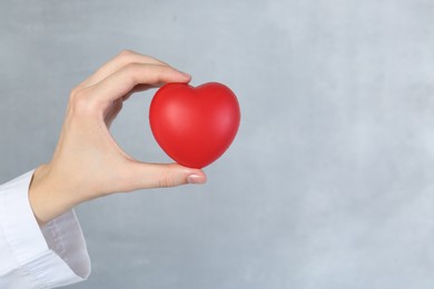 Photo of Woman holding red heart on grey background, closeup. Space for text