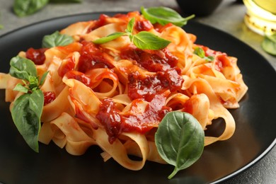 Photo of Delicious pasta with tomato sauce and basil on grey table, closeup