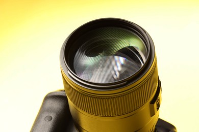 Photo of One modern photo camera on yellow background, closeup