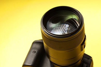 Photo of One modern photo camera on yellow background, closeup