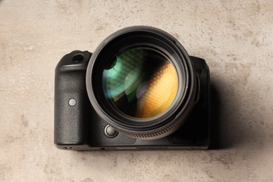 Modern photo camera on light grey table, above view