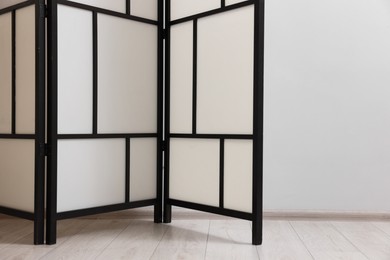 Folding screen near white wall indoors, space for text. Interior element